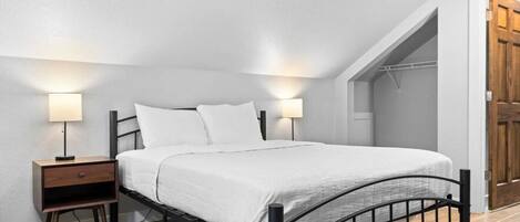 Une chambre à coucher avec un lit, des tables de chevet et des lampes fixées au mur.