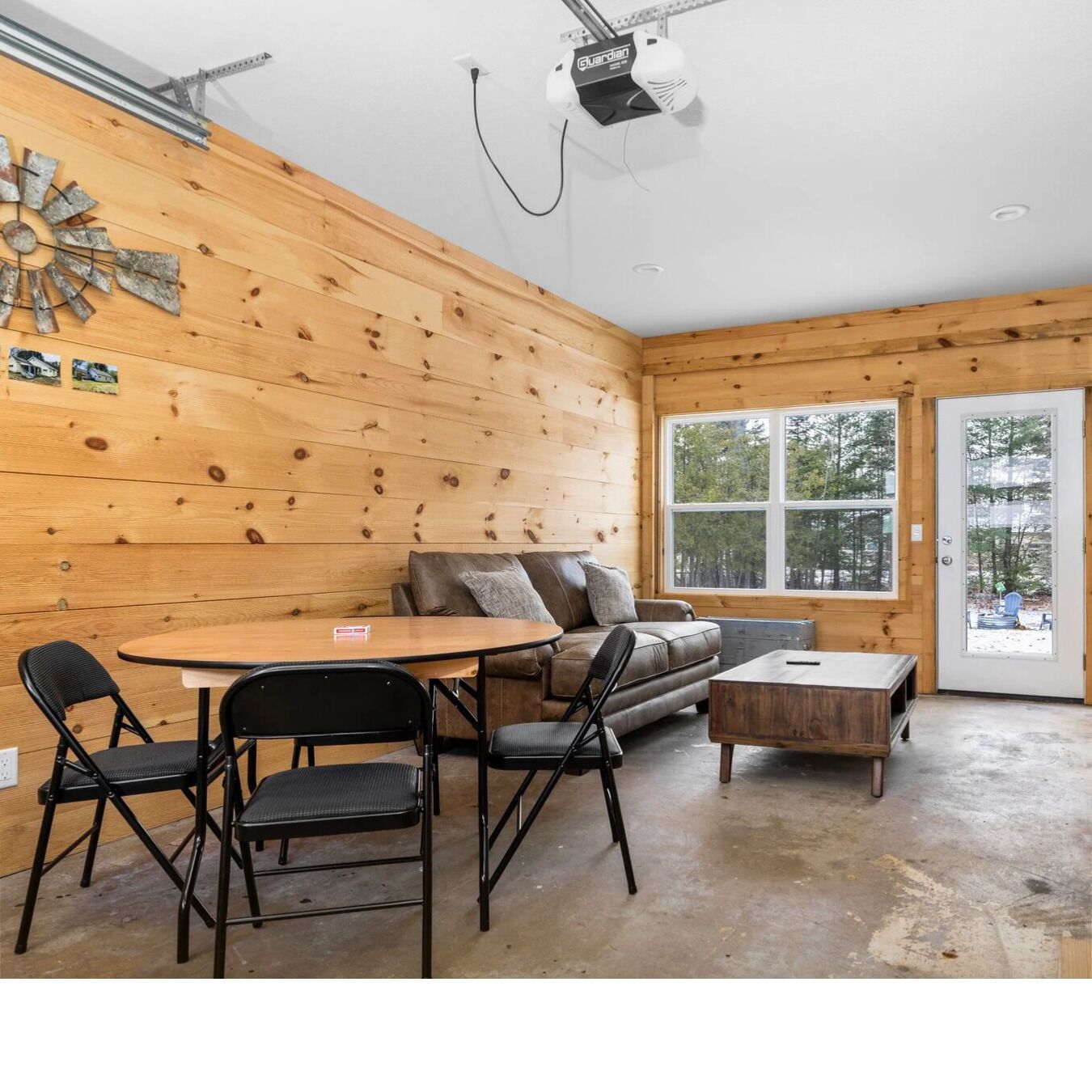 Ett mysigt rum med träinredning, en soffa, ett soffbord och ett matbord med stolar.
