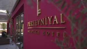 Une enseigne d’hôtel avec les noms « PERTEVNIYAL » et « AZIZEE HOTTEL » sur un mur rose.