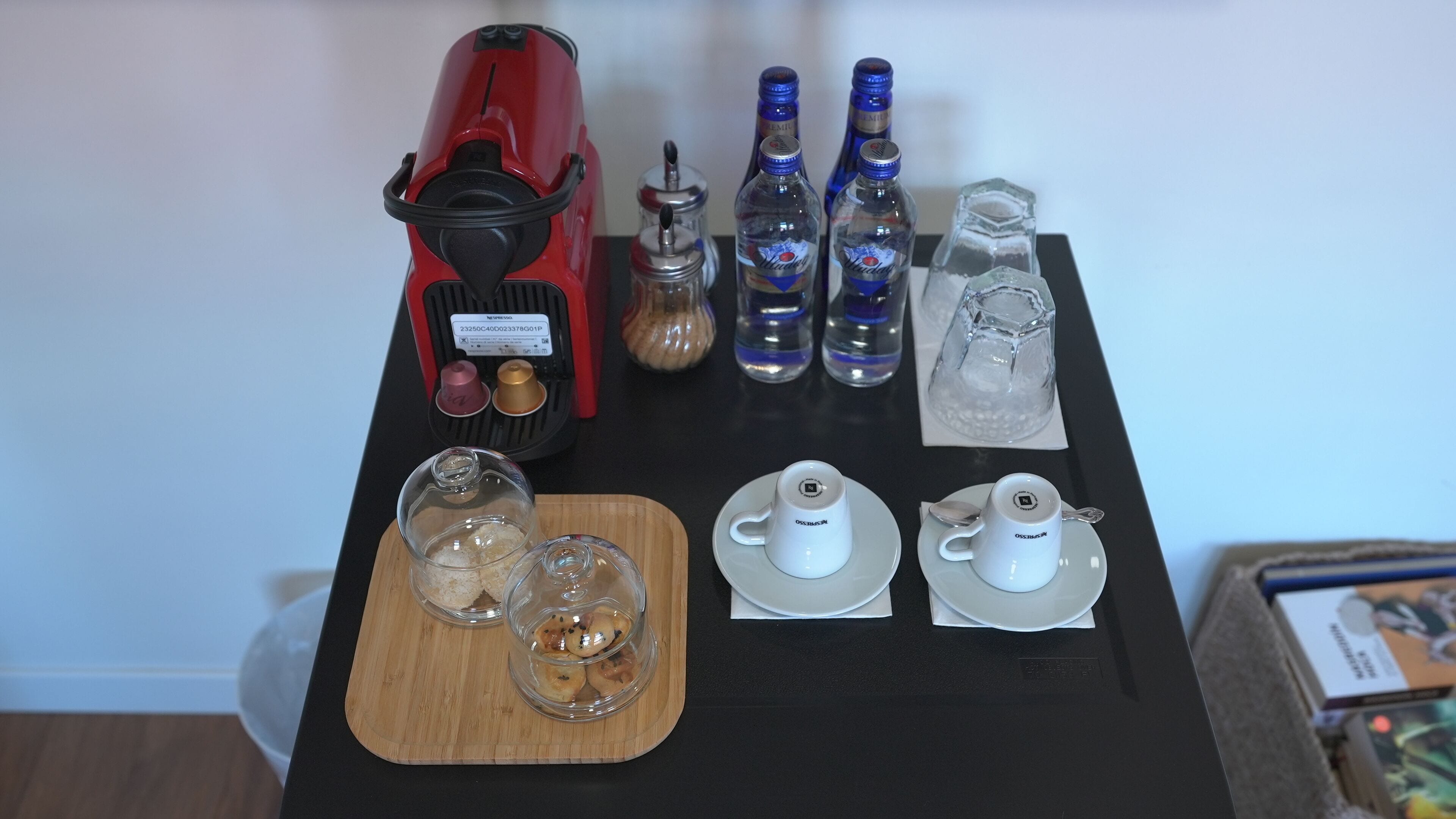 A coffee machine, bottles of water, a glass pitcher, and two teapots on a table.