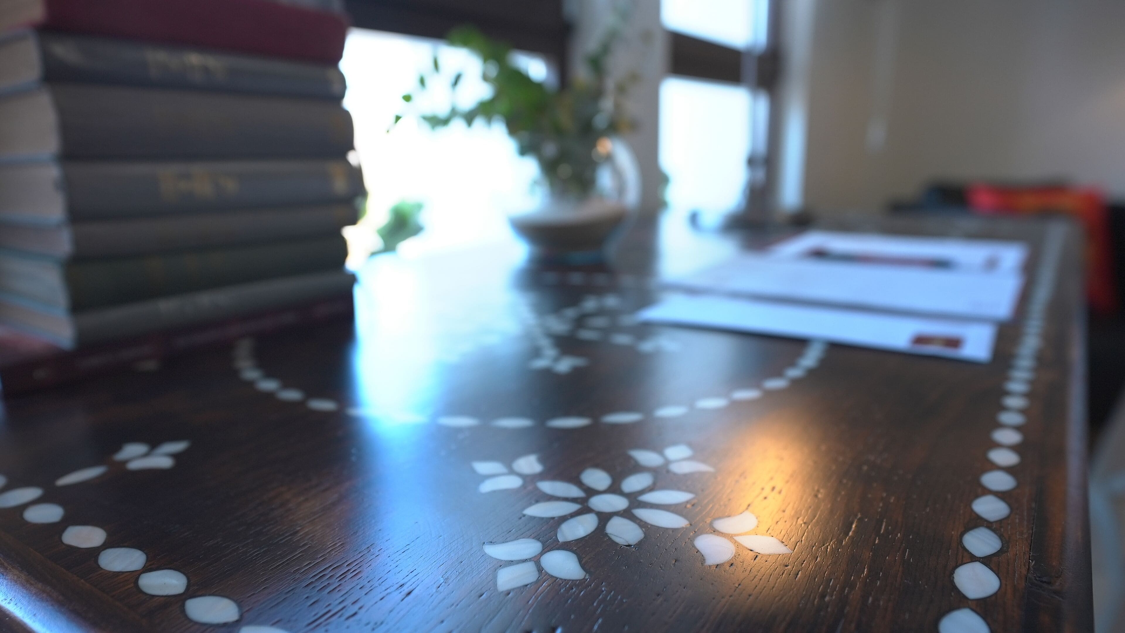 Uma mesa de madeira com padrão floral e objetos brancos espalhados.