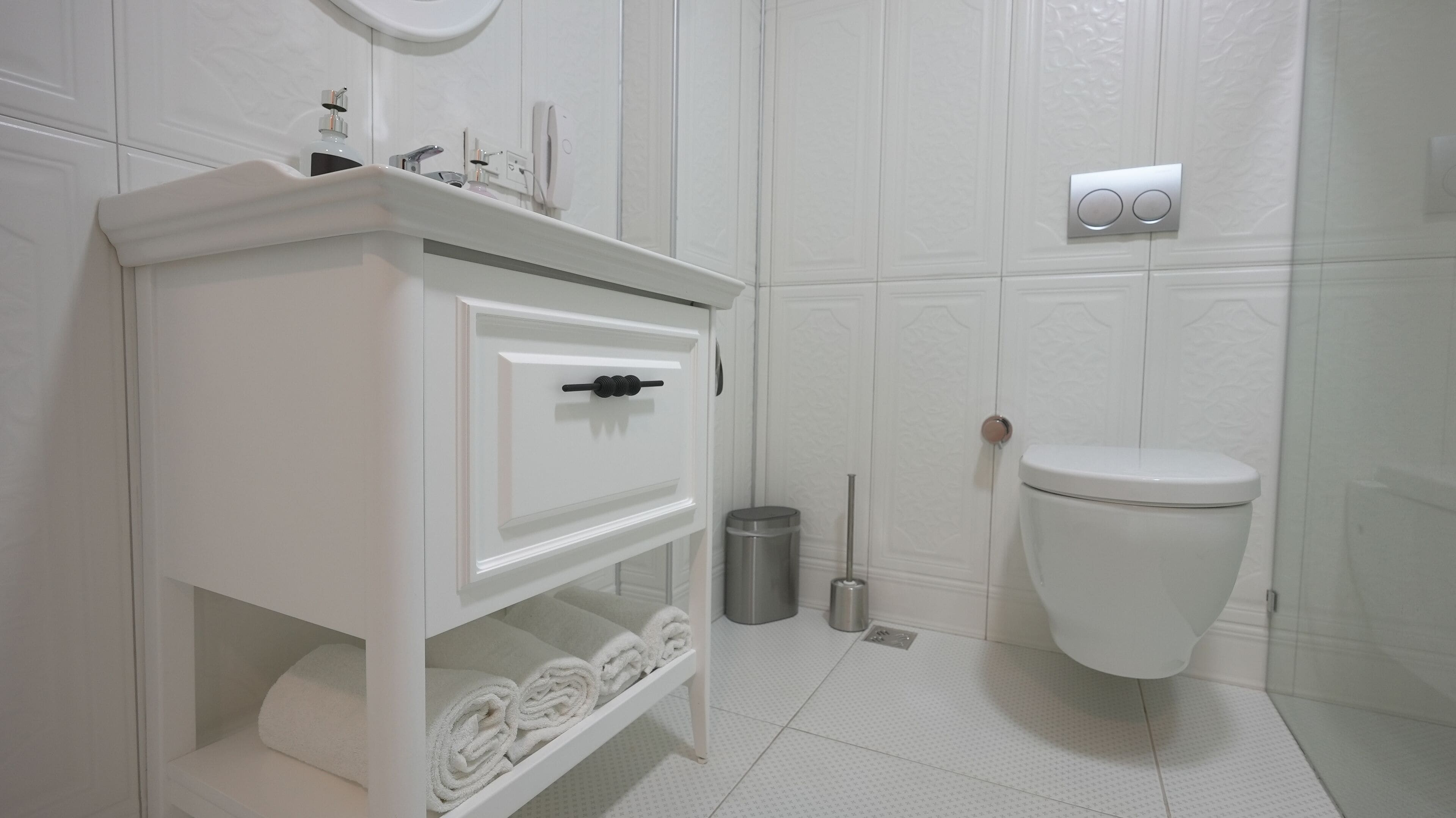 Un baño blanco con tocador, inodoro y un cubo de basura.