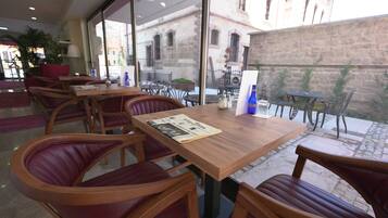 Um restaurante com mesas de madeira e cadeiras de couro vermelho, um jornal sobre uma mesa e uma garrafa de água.