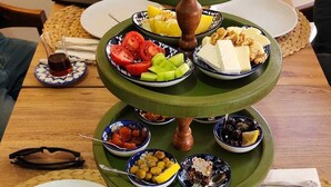 Un plateau de service à trois niveaux, sur lequel sont disposés divers aliments et condiments, posé sur une table en bois.