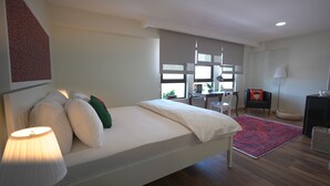 Une chambre à coucher avec un lit, un bureau, une chaise et une lampe.