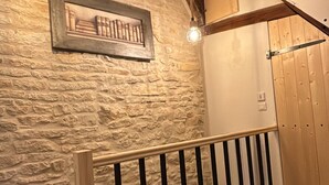 A wooden staircase with a stone wall and a framed picture above it. - La Maison de Pierre (Chablis)
