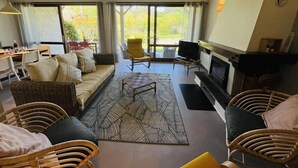 A spacious living area with a sofa, chairs, a fireplace, and a television. - Villa "Calypso" (SEIGNOSSE)