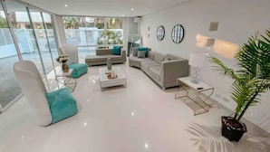 Ein modernes Wohnzimmer mit einem weißen Sofa, Türkis-Armstühlen und einem Couchtisch.