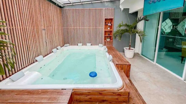 Ein Whirlpoolbereich mit Holzterrasse, Glasumrandung und einer Topfpflanze.