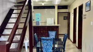 A hotel lobby with a staircase, a reception desk, and a dining area with blue chairs. - Prédio Atalaia  (Arraial do Cabo)