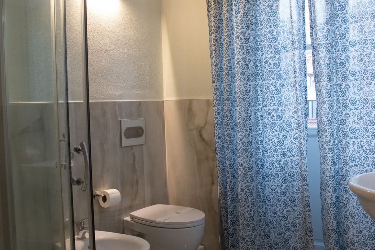 A bathroom with a glass shower enclosure, a toilet, and a sink.