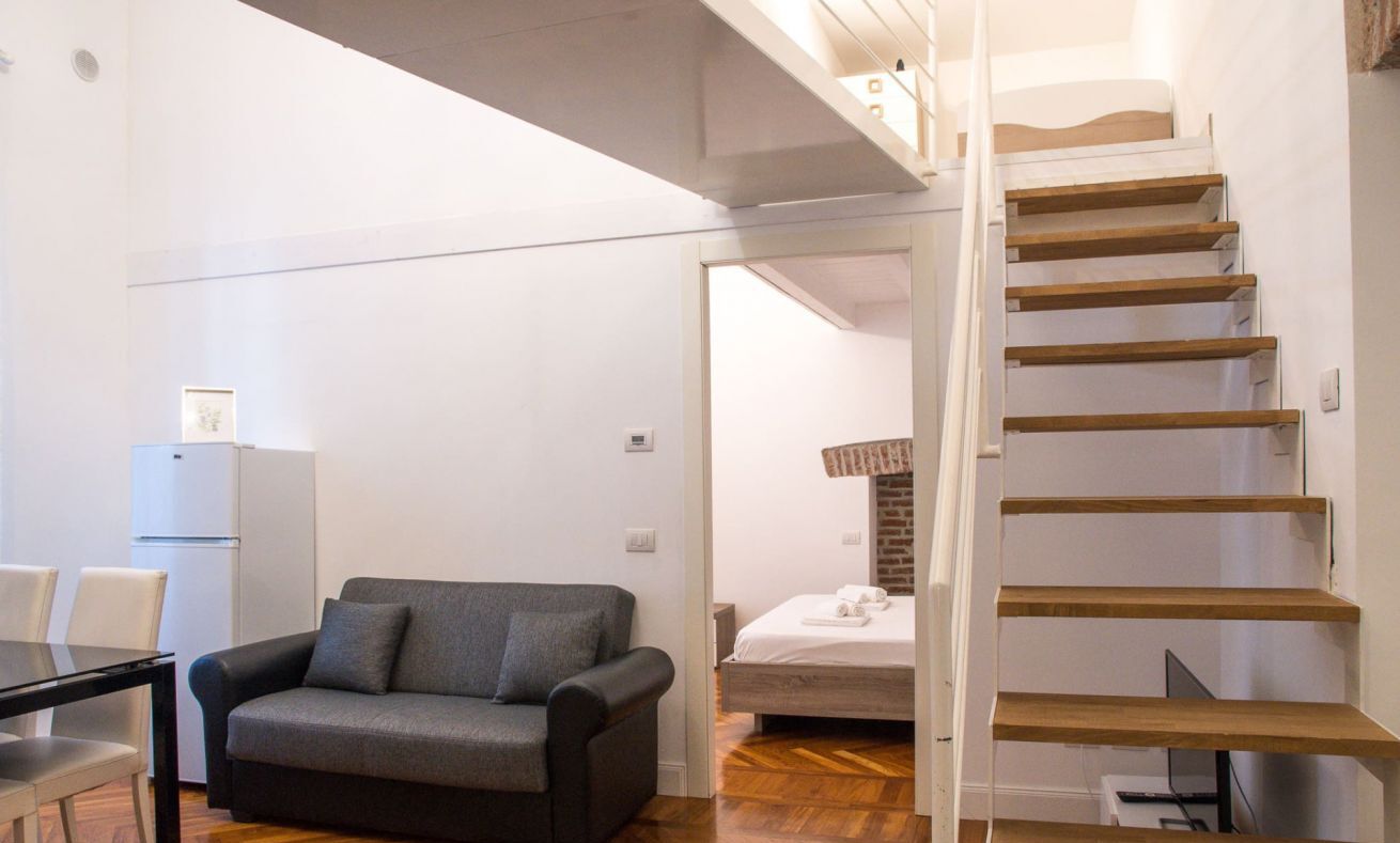 Eine moderne Wohnung mit Treppe, Sofa, Esstisch und Bett.