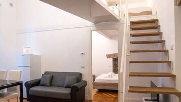 Eine moderne Wohnung mit Treppe, Sofa, Esstisch und Bett.
