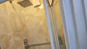 A shower area with beige tiles, a glass door, and a showerhead.