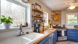 Een moderne keuken met een grote spoelbak, houten planken, een fornuis en blauwe kastjes.
