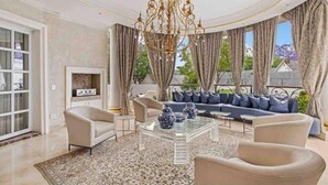 Un salon luxueux agrémenté d’un grand lustre, d’un ensemble de canapés et d’une table basse.