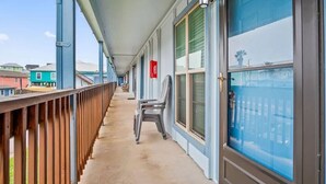 Ein überdachter Balkon mit Holzgeländer, einem Stuhl und einer Tür mit Fensterglas.