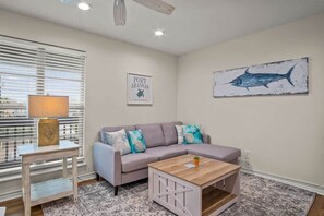 A living room with a grey sofa, a wooden coffee table, a lamp, and a framed picture of a fish on the wall. - Seagull 26- Newly Renovated | Close to Beach (Port Aransas)