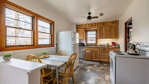 A kitchen with wooden cabinets, a white refrigerator, a stove, and a dining area with a table and chairs.