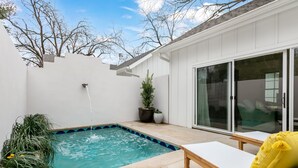 A backyard with a swimming pool, a bench, and a sliding glass door leading to a patio. - Bijou: Collette | Luxury Cottage | Plunge Pool | Full Kitchen | Seasonal Fireplace (Fredericksburg)