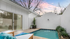 A backyard with a swimming pool, a wooden bench, and potted plants. - Bijou: Chloe | Luxury Cottage | Plunge Pool | Full Kitchen | Seasonal Fireplace (Fredericksburg)