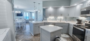 A modern kitchen with grey cabinets, stainless steel appliances, and a large island.
