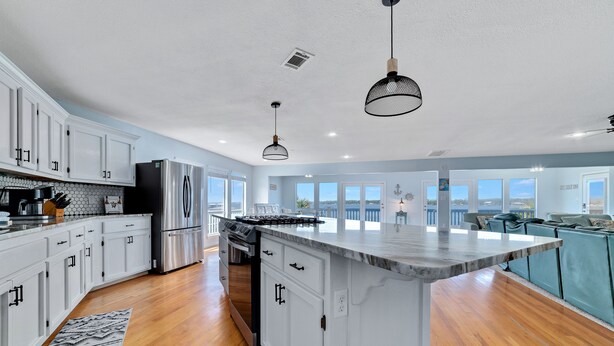 A spacious kitchen with white cabinetry, a large island, and a view to the living area. - WATERFRONT, PRIVATE POOL, GREAT FOR FAMILES & DOG FRIENDLY! (Gulf Shores)