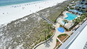 Un hotel sulla spiaggia con piscina, ombrelloni e vista sull'oceano.