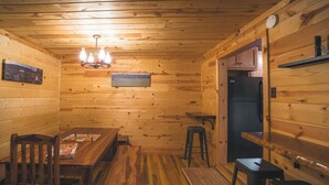 Un interior de madera con una mesa de comedor, sillas, un banco, un taburete y un refrigerador.