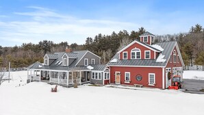 Ein großes, zweistöckiges Haus mit rotem Anstrich und grauem Dach, mit einer Veranda und einer Garage.
