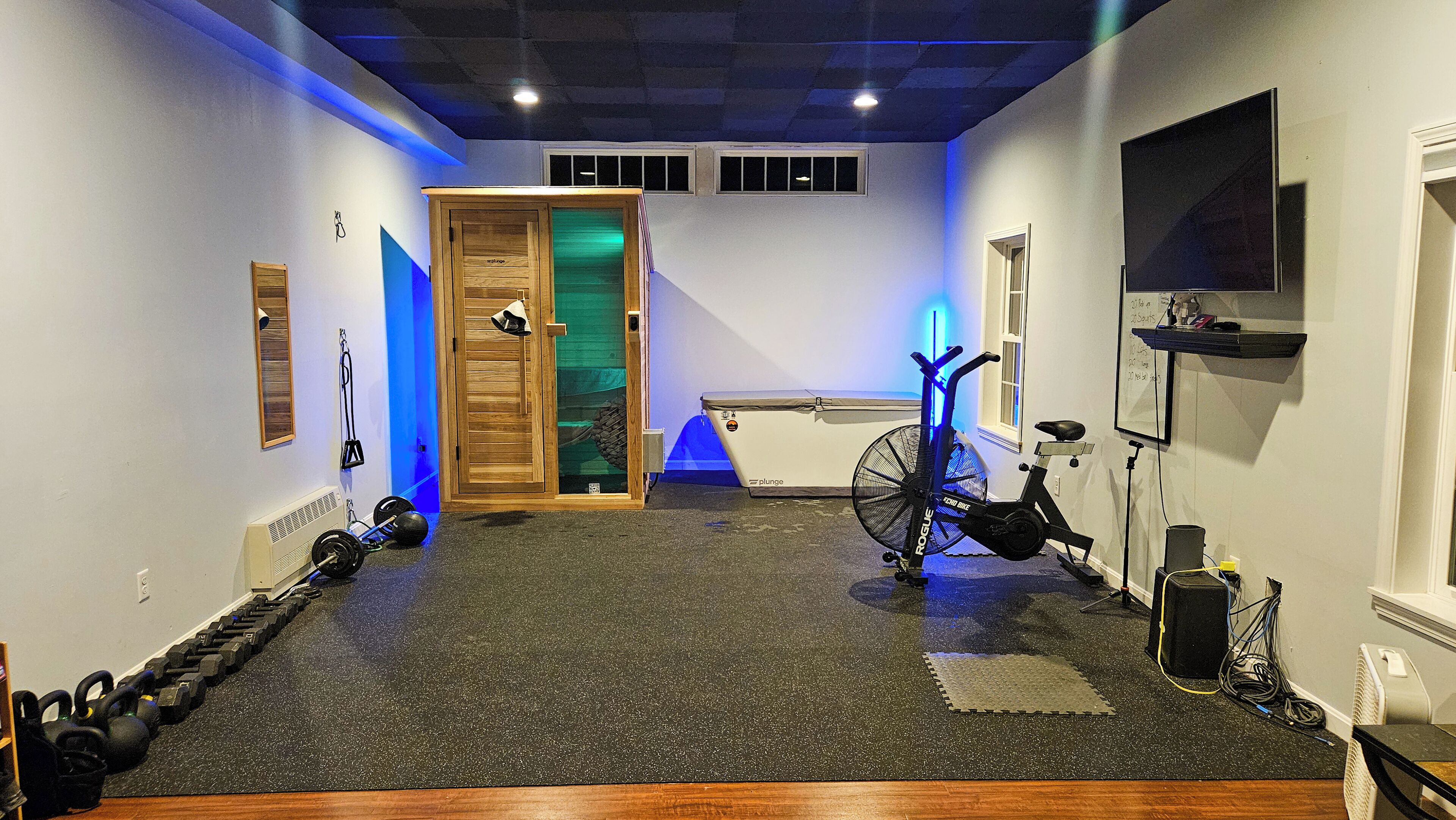 A home gym with exercise equipment including a stationary bike, weights, and a treadmill.