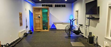 A home gym with exercise equipment including a stationary bike, weights, and a treadmill.