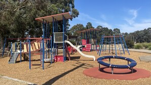 A playground with various play structures, including slides and climbing frames, surrounded by trees. - House in Thomastown (Thomastown)