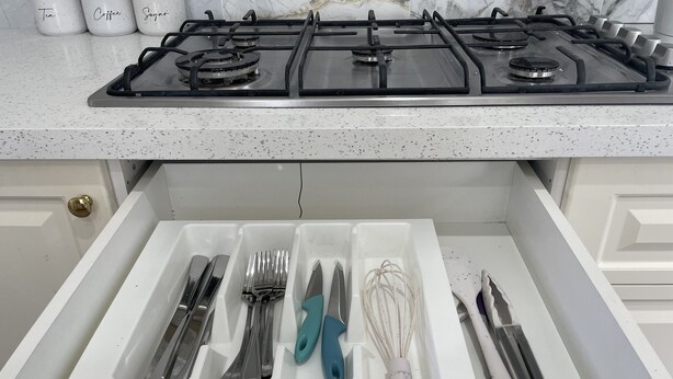 A kitchen with a gas stove, a drawer organizer with utensils, and three jars labeled "Tea," "Coffee," and "Sugar." - House in Thomastown (Thomastown)