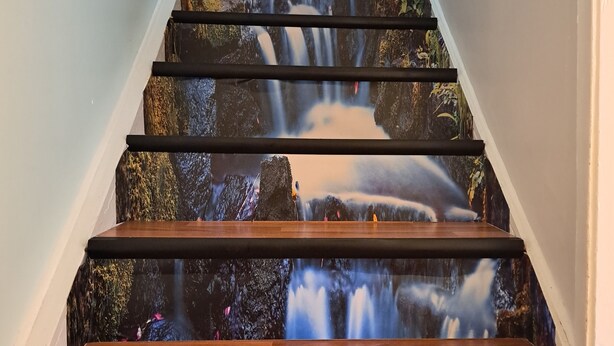 Un escalier dont les marches sont décorées d’une fresque représentant une cascade.