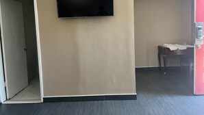A room with a flat-screen TV mounted on the wall, a door leading to another room, and a small table with a chair. - Pomona Inn (Pomona)