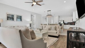 Een moderne woonkamer met een bank, salontafel en een eethoek met stoelen.