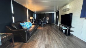 Een moderne woonkamer met een leren bank, een flatscreen televisie en een eethoek met stoelen.