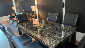 Een eetgedeelte met een marmeren tafel, zwarte lederen stoelen en twee tafellampen.