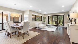 A spacious living room with a dining area, large windows, and a view of the outdoors.