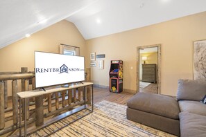A living room with a television, a gaming console, and a couch. - New Log Cabin with Private Hot Tub, Free Daily Activities, Arcade & Shuffleboard (Branson)