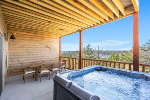A wooden deck with a hot tub, wooden furniture, and a view of the landscape. - New Log Cabin with Private Hot Tub, Free Daily Activities, Arcade & Shuffleboard (Branson)