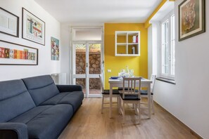 Un soggiorno moderno con un divano, un tavolo da pranzo con sedie, una parete color giallo e una parete in pietra.