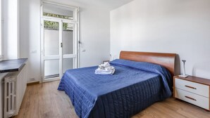 A bedroom with a bed, a nightstand, a radiator, and a door leading to a balcony. - Comfortable apartment perfect for 4 people and surrounded by greenery, it is located in a quiet area, a few steps from the beaches of Lerici. The house is equipped with every comfort, 2 bathrooms, kitchen, TV, WiFi, private parking. Ideal opportunity to  (Lerici)