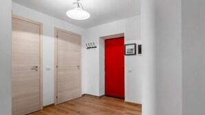 A hallway with wooden flooring, two wooden doors, a red door, and a light fixture. - Comfortable apartment perfect for 4 people and surrounded by greenery, it is located in a quiet area, a few steps from the beaches of Lerici. The house is equipped with every comfort, 2 bathrooms, kitchen, TV, WiFi, private parking. Ideal opportunity to  (Lerici)