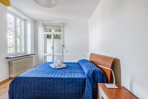 A room with a bed, a bedside table, a window, and a radiator.