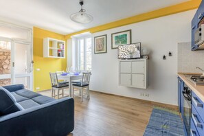 A modern apartment with a dining area, a sofa, a kitchen, and a view of the outside.