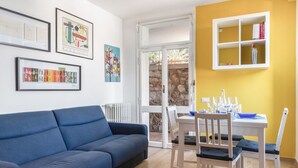 A room with a blue sofa, a dining table with chairs, a window with a view, and framed artwork on the wall. - Comfortable apartment perfect for 4 people and surrounded by greenery, it is located in a quiet area, a few steps from the beaches of Lerici. The house is equipped with every comfort, 2 bathrooms, kitchen, TV, WiFi, private parking. Ideal opportunity to  (Lerici)