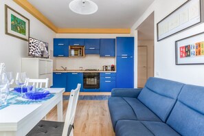 Une cuisine moderne avec des meubles de rangement bleus, une table à manger avec des sets de table bleus et un canapé bleu.