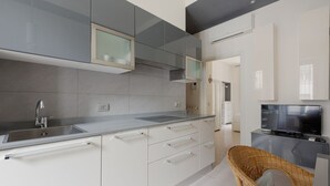 A modern kitchen with a built-in sink, white cabinets, and a television.